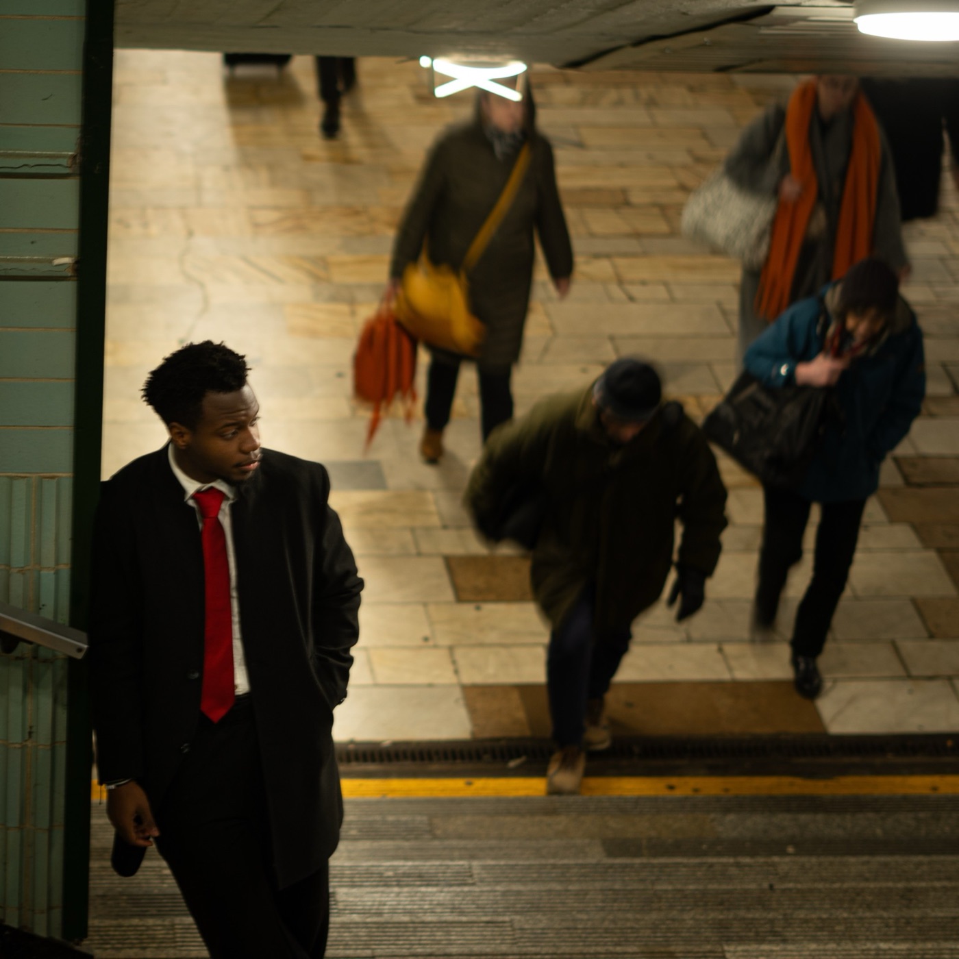 Kessy Janabi in a red tie on the stairs of a metro station